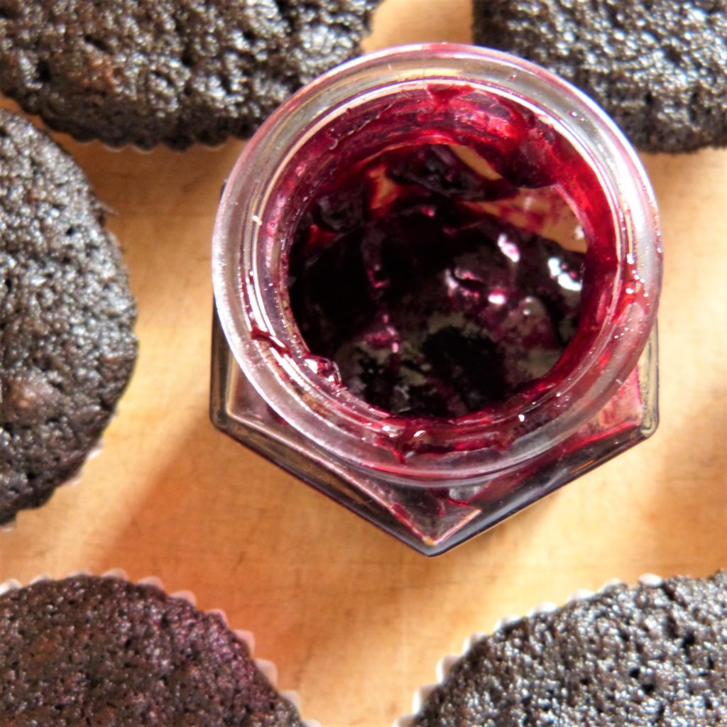 jar of elderberry jelly with chocolate muffins