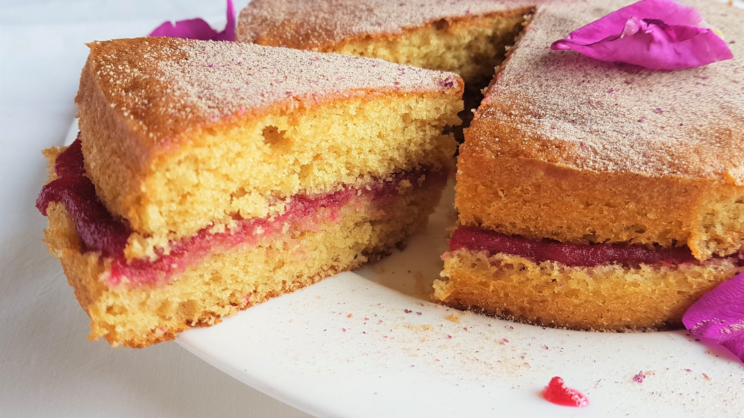 Slice of homemade sponge cake sandwiched with rose preserve