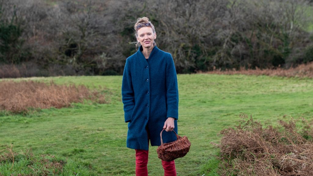 Forager Rachel Lambert standing in a field in autumn with a basket